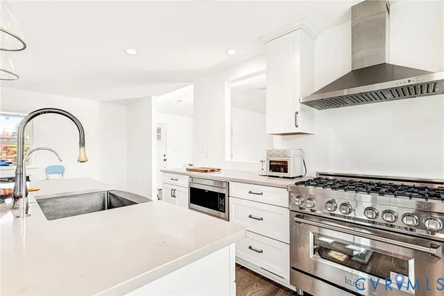 a kitchen with stainless steel appliances granite countertop a stove a sink and a white wooden cabinets