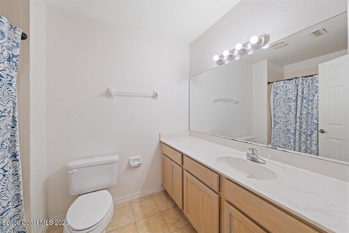 110 Colibri Way, Unit 107 Melbourne, FL 32901 - Photo 18 of 27 a bathroom with a toilet a sink a mirror and vanity