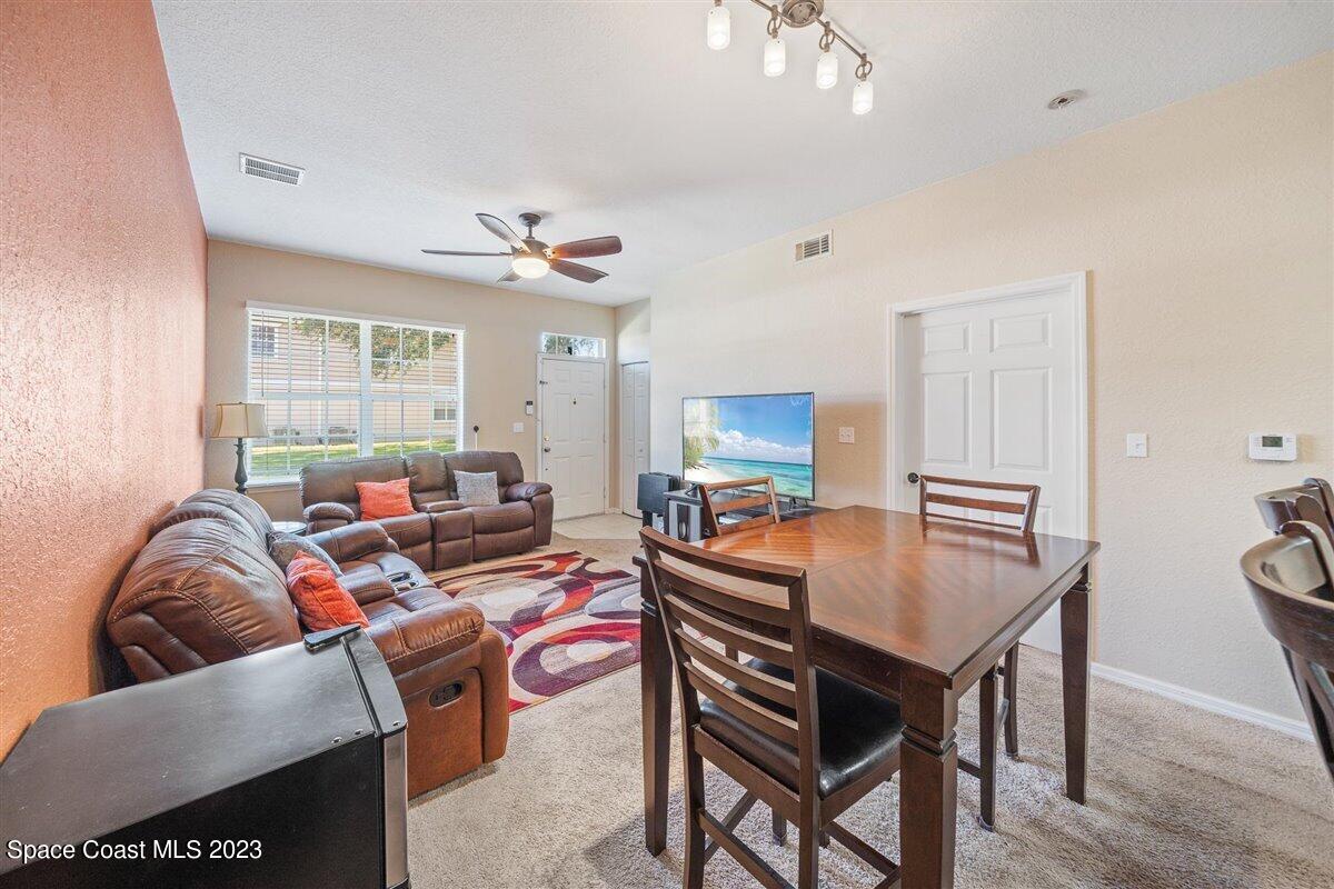 110 Colibri Way, Unit 107 Melbourne, FL 32901 - Photo 8 of 27 a living room with furniture a chandelier and a flat screen tv