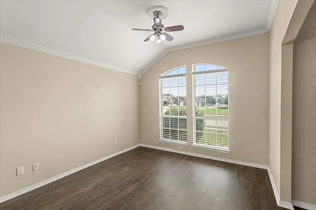 an empty room with wooden floor chandelier fan and windows