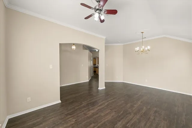 a view of an empty room with wooden floor and a ceiling fan
