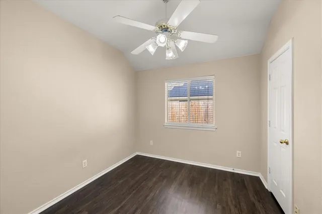 an empty room with wooden floor chandelier fan and window