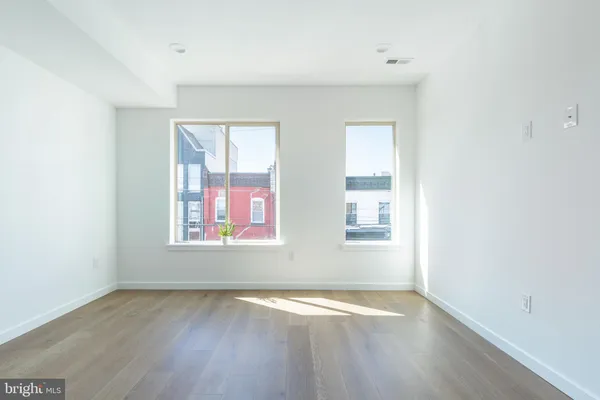 an empty room with wooden floor and windows