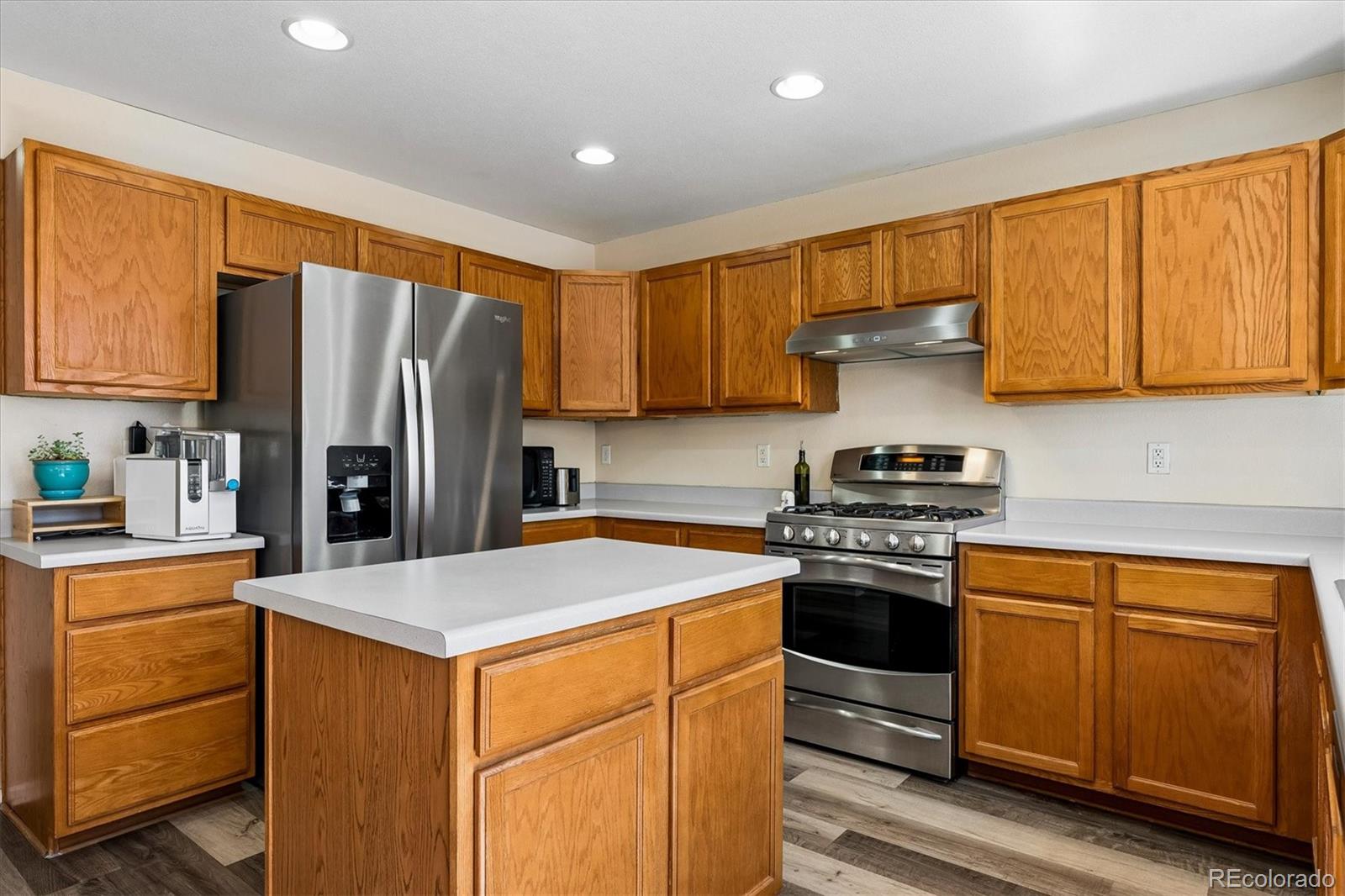 10534 Westcliff Place Highlands Ranch, CO 80130 - Photo 15 of 38 a kitchen with stainless steel appliances granite countertop a refrigerator stove a sink dishwasher and wooden cabinets with wooden floor