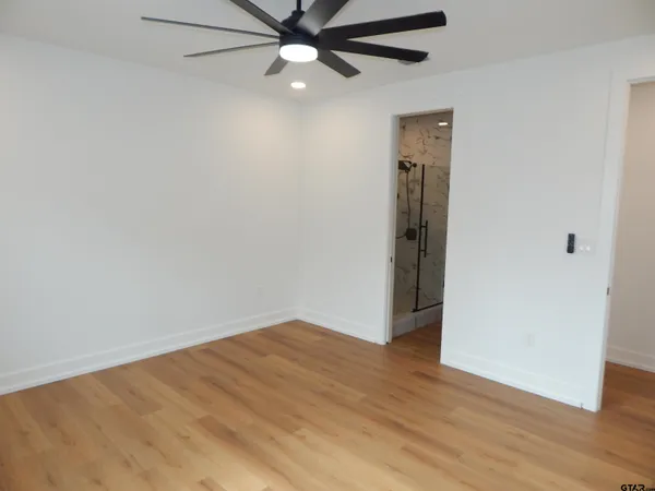 an empty room with wooden floor closet and fan