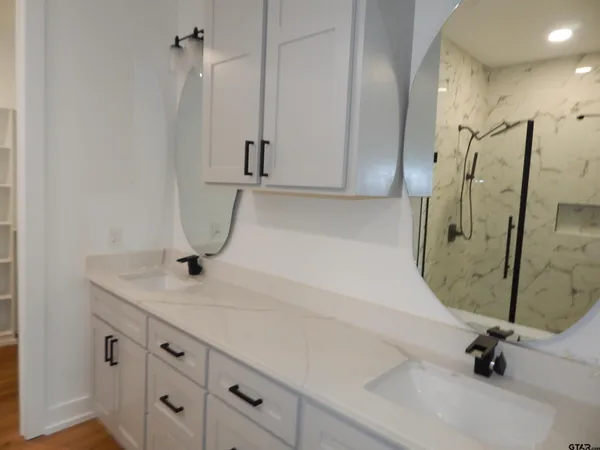 a bathroom with a granite countertop sink a mirror and shower