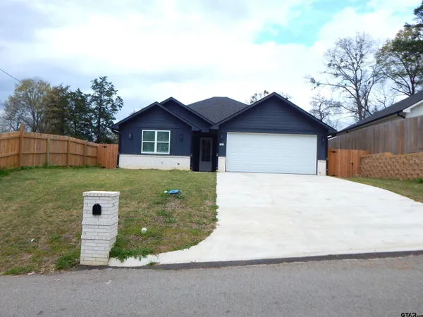 a front view of a house with a garden and tree