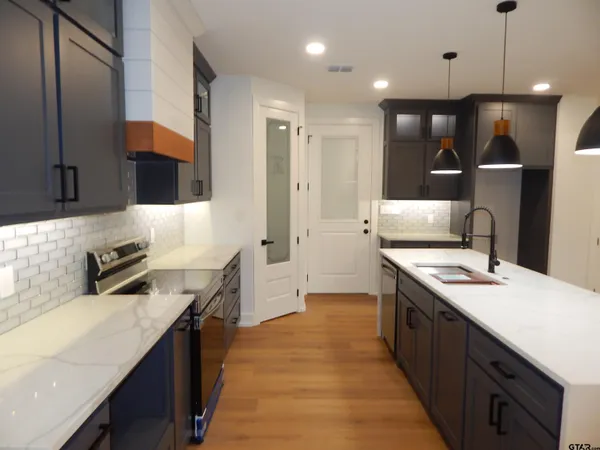 a kitchen with stainless steel appliances granite countertop a sink a stove and a refrigerator