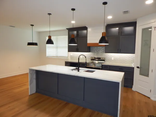 a kitchen with kitchen island a sink stainless steel appliances and cabinets