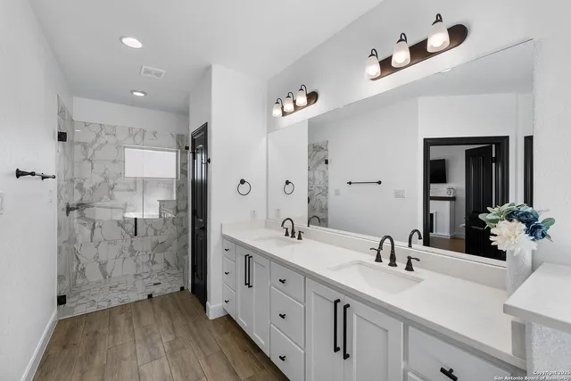 a bathroom with a double vanity sink a mirror and shower