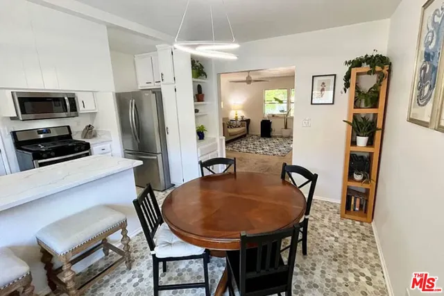 a kitchen with stainless steel appliances a dining table chairs and refrigerator