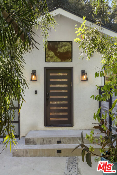 9782 Oak Pass Road Beverly Hills, CA 90210 - Photo 3 of 27 a front view of a house with a tree