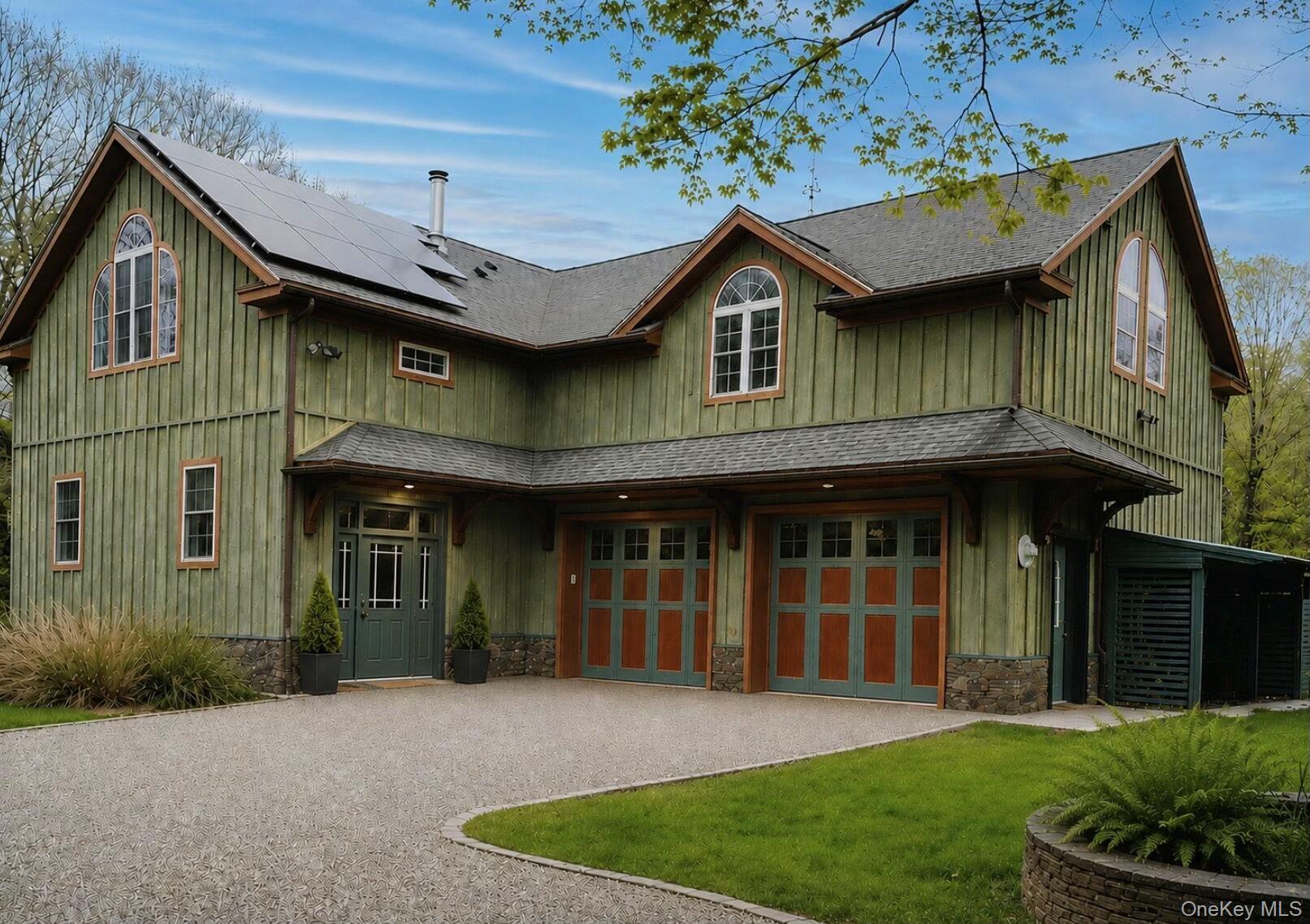92 Fiddlers Bridge Road Staatsburg, NY 12580 - Photo 1 of 32 Vertical wood siding exterior with stone foundation detailing, featuring a two-car garage with teal and orange paneled doors