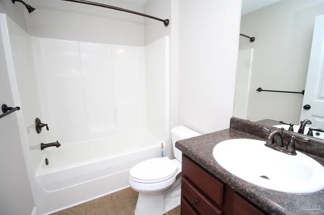 a bathroom with a granite countertop sink toilet mirror and bathtub