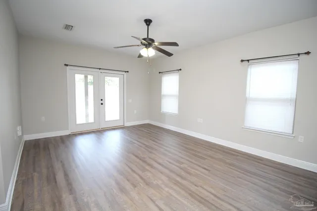 a view of an empty room with wooden floor and a window