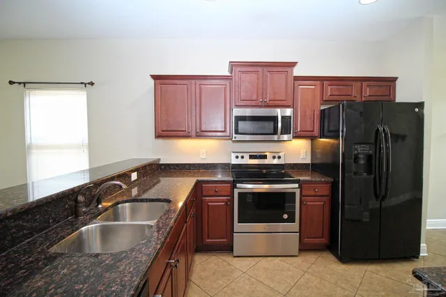 a kitchen with granite countertop a refrigerator and a sink
