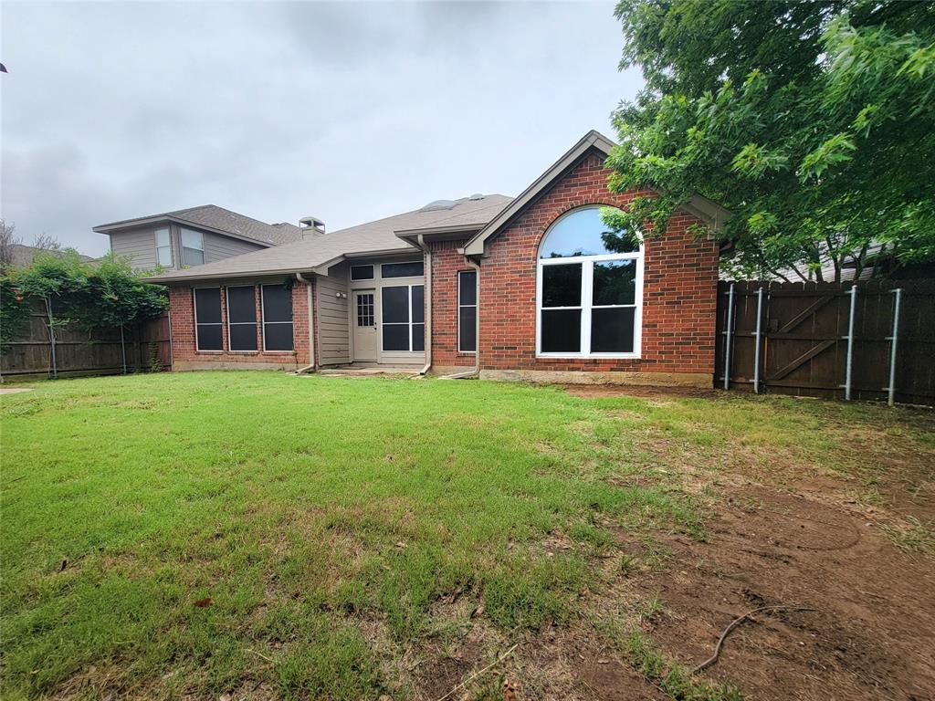 1604 Knoll Ridge Circle Corinth, TX 76210 - Photo 36 of 37 Expansive backyard featuring a manicured lawn, red brick exterior, and a prominent arched window