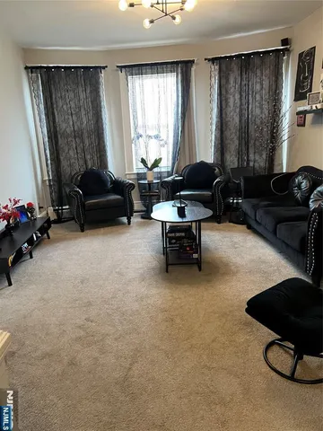 a living room with furniture a chandelier a large window and potted plants