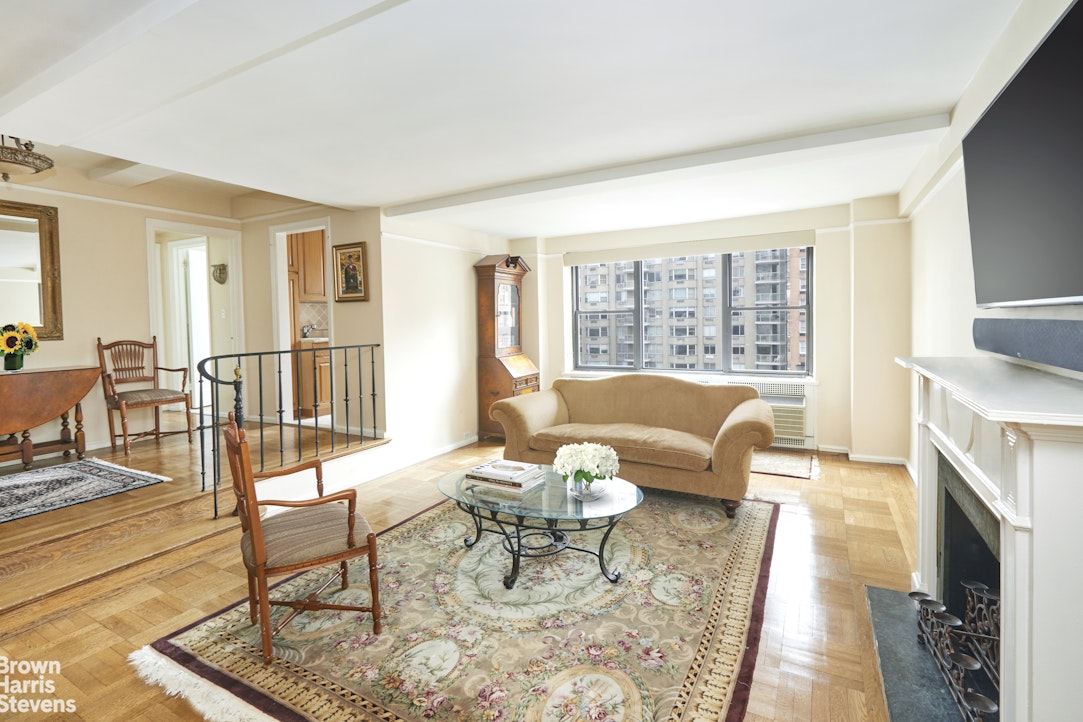 235 East 73rd Street, Unit 8D Manhattan, NY 10021 - Photo 3 of 9 a living room with furniture a fireplace and a floor to ceiling window