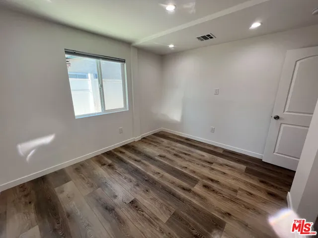 an empty room with wooden floor and window