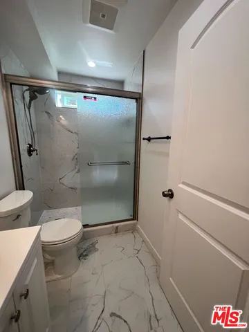 a bathroom with a granite countertop shower and a toilet