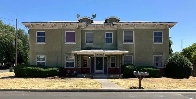 a front view of a house with garage and plants