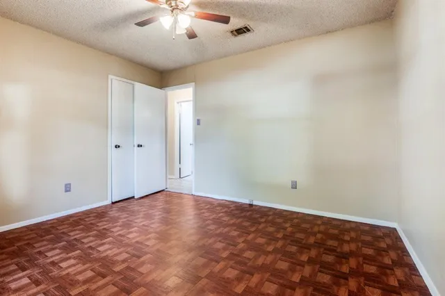 an empty room with a chandelier fan and windows