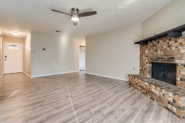 a view of empty room with wooden floor and fireplace