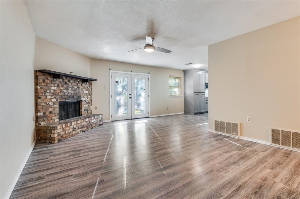 628 Thompson Street Everman, TX 76140 - Photo 5 of 24 a view of an empty room with wooden floor fireplace and a window