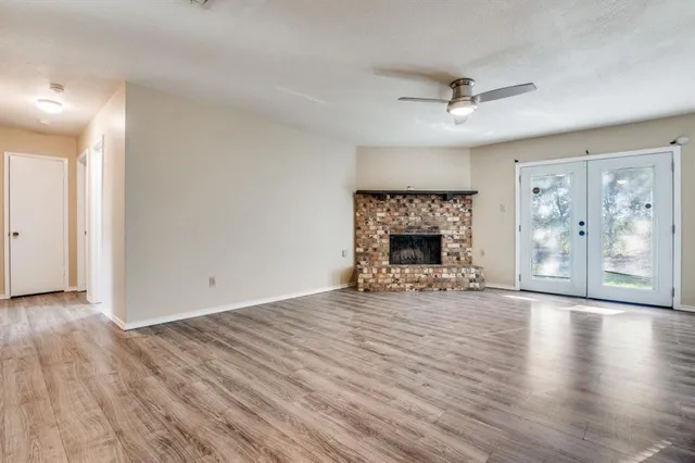 an empty room with wooden floor fireplace and windows