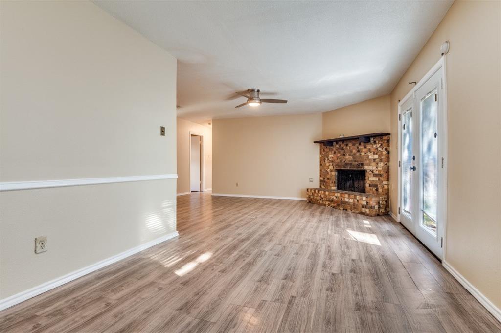 628 Thompson Street Everman, TX 76140 - Photo 9 of 24 wooden floor in an empty room with a fireplace