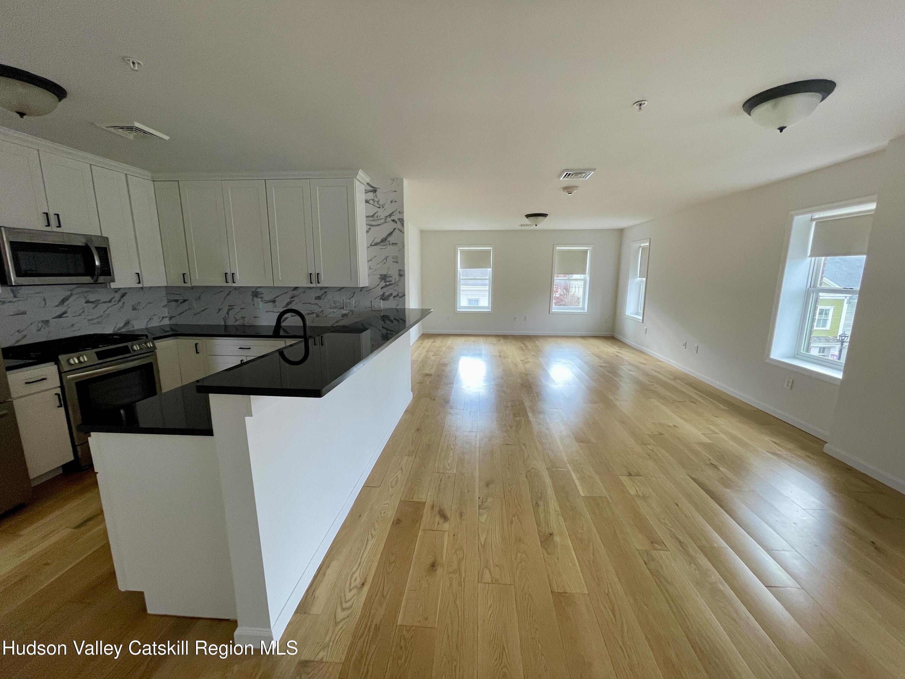 202 Warren Street, Unit 2 Hudson, NY 12534 - Photo 6 of 17 a view of a kitchen with cabinets stainless steel appliances wooden floor and a window