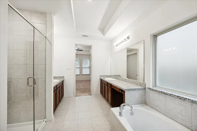 an empty room with chandelier fan and windows