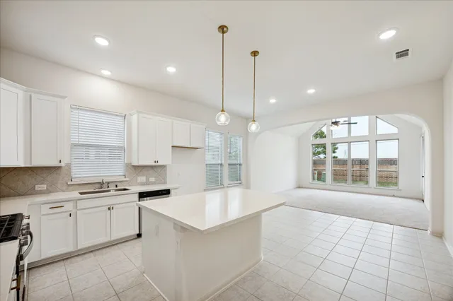 a large white kitchen with kitchen island a large window a sink and a counter top space