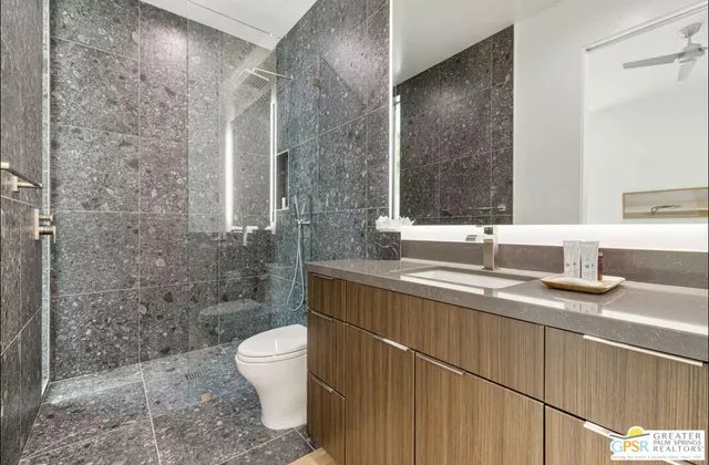 a bathroom with a granite countertop sink a toilet and a mirror