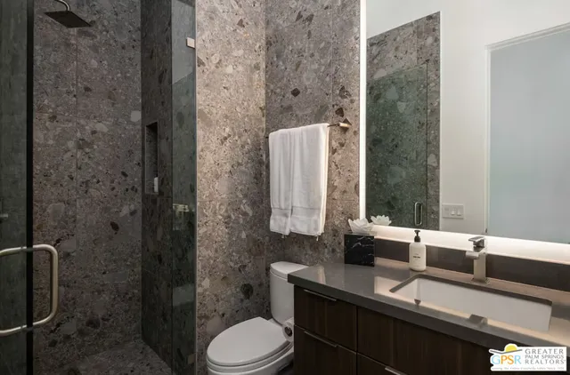 a bathroom with a granite countertop sink a toilet and a mirror