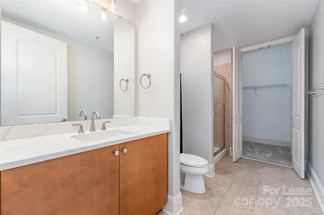 a bathroom with a granite countertop sink a toilet a mirror and shower