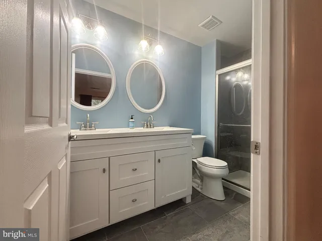 a bathroom with a toilet a double vanity sink and a mirror