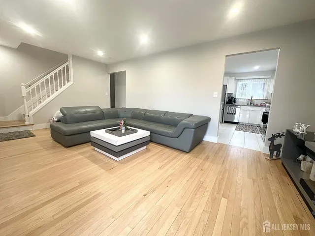 a kitchen with stainless steel appliances kitchen island granite countertop a refrigerator a stove a sink a dining table and chairs with wooden floor