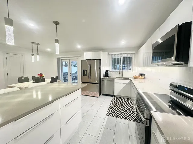 a kitchen with stainless steel appliances granite countertop a dining table chairs and refrigerator