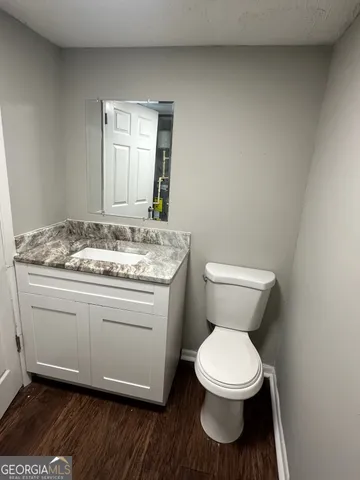 a bathroom with a granite countertop toilet a mirror and a sink