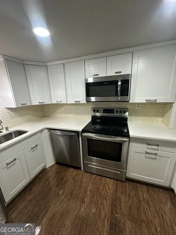 a kitchen with granite countertop a stove a microwave a sink and cabinets