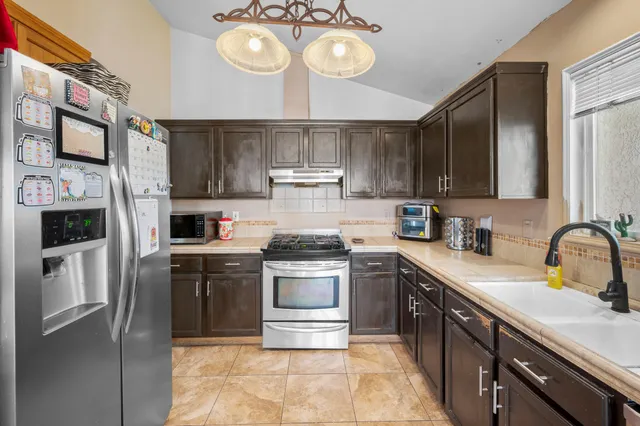 a kitchen with stainless steel appliances granite countertop a sink a stove a refrigerator and a microwave