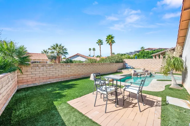 a view of a patio with table and chairs with plants and wooden fence