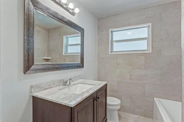 a bathroom with a granite countertop sink a toilet and a mirror
