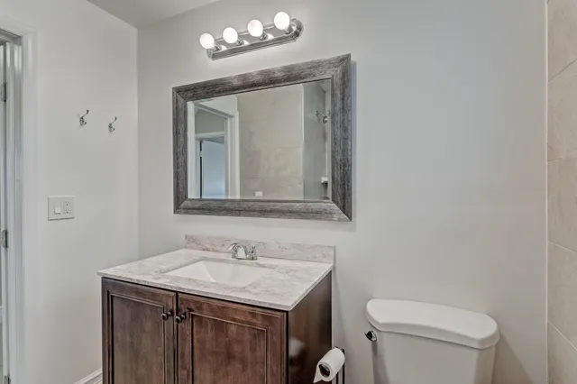 a bathroom with a granite countertop toilet a sink and a mirror