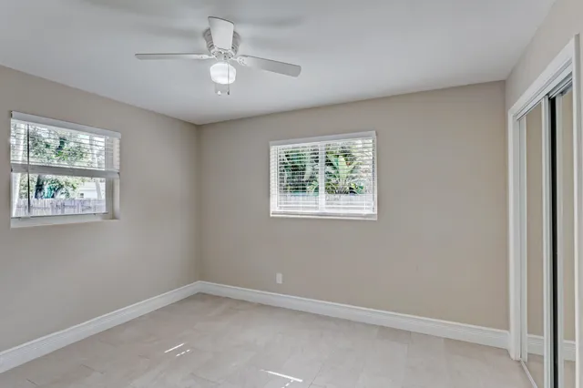 an empty room with windows and ceiling fan