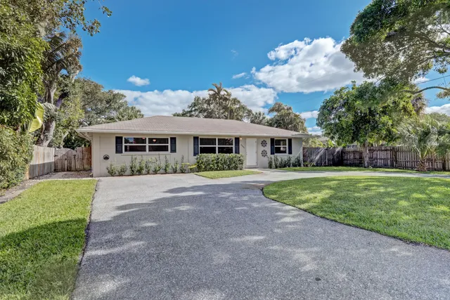 a front view of a house with a garden and trees