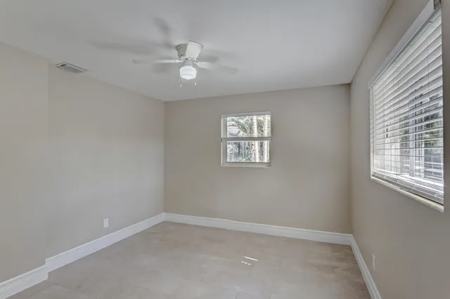 an empty room with windows and fan