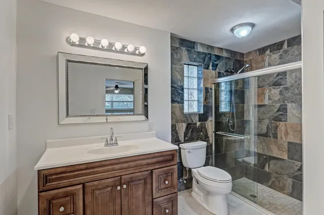 a bathroom with a sink a toilet a mirror and shower